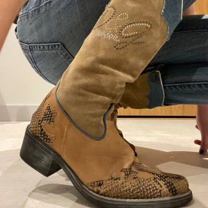 Dolce & Gabbana boots - Säljer nu mammas unika Dolce Gabbana boots. Inköpa i London för ca 4000kr, använda endast några få gånger, så i toppskick! Många unika detaljer och snygg lila insida💜💜allmänt fin kvalité och snyggt till det mesta!