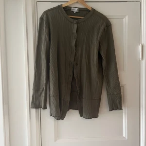 Grön tröja - En grön tröja med knappar och lite… lockig kant(?) (vet inte vad det kallas)