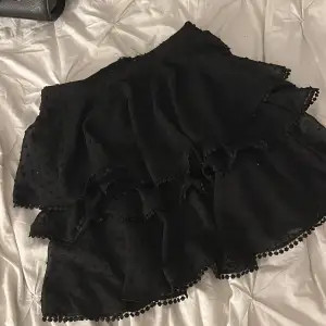 En svart gullig volang kjol med prickar på, den har ett till lager under volangerna så väldigt säker kjol. Väldigt bra skick och har inte alls använts mycket . 