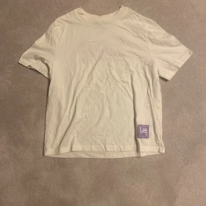 Lee T-shirt - Vit Lee T-shirt med lila detaljer köpt från H&M! Står ej någon storlek men skulle säga att dne passar S/M
