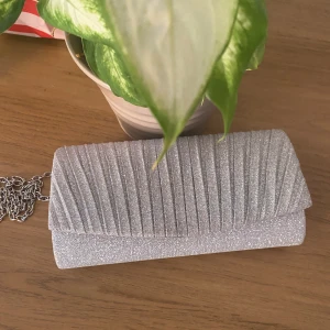 Glittrig kuvertväska  - Glitter väska med måtten 20x12. Kommer med långa band, men som går att ta av(se bild) Endast använd en gång, i jättebra skick