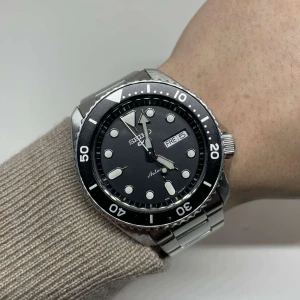 Seiko 5 Sports Automatic - Svart - Seiko 5 Sports Automatic i mycket gott skick, klockan kommer med alla tillbehör. Nypris: 3598:- Vårt pris: 2149:- Tveka inte att skriva till oss  vid frågor eller funderingar!