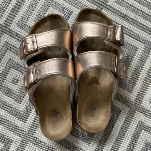 Beiga tofflor - Jättefina inne och ute tofflor med lite glitterbeige på dem. Har används en del men fortfarande i väldigt bra skick. Storlek 37-38.