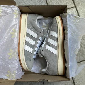Adidas Campus 00’s - Säljer mina helt nya och oanvända Adidas Campus 00’s ”Grey White”. Säljer då dom var för småa och inte går att skicka tillbaka. Dom är endast provade. Storlek: 40. Pris: 1 600kr + frakt. Skicka ett meddelande vid intresse och frågor! 