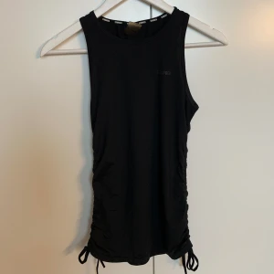 Träningslinne med detalj - Träningslinne från Stronger med detaljer i sidan, band som går att dra ihop. Fint skick. 🖤