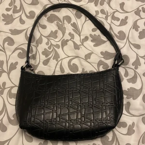 Liten svart handväska  - Helt ny! Liten väska med tillhörande axelband, fick i present, inte min stil 