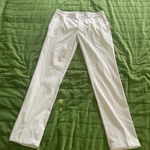 J.Lindberg byxor  - Säljer ett par stilrena vita golfbyxor från J. Lindberg. De är i storlek 32 och i mycket gott skick. Perfekta både för golfbanan och som en del av en snygg vardagsoutfit.  
