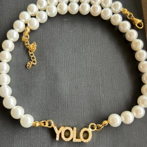 YOLO (you only live once) halsband med imiterade pärlor - YOLO (you only live once) halsband med imiterade pärlor Material: Imiterade pärlor och rostfritt stål! Helt ny! Storlek:42 cm(justerbar)