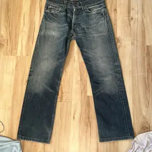 Ett par jeans från Levis som inte kommit till användning. Dem är lite grå/mörkblåa och lite mönster på baksidan.