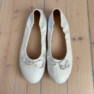 Vita ballerinaskor - Coquette vita ballerinaskor i läder med rosetter passar storlek 36-38. Nästan aldrig använt skriv privat om du har frågor😊
