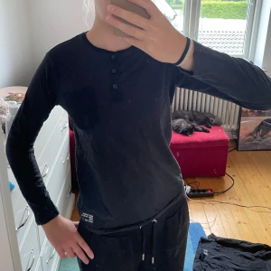 Svart långärmad tröja från KappAhl - Säljer en svart långärmad tröja från KappAhl. Den har en knappdetalj vid halsen och en liten bröstficka. Perfekt för höst och vinter, och den är i bra skick. Passar både till vardags och lite mer avslappnade tillfällen. Skön och bekväm att ha på sig!