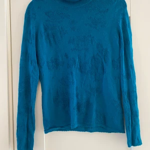 Turkos tunn stickad polo fr Kenzo i strl S - Väl använd tröja. Finns lagningar under båda ärmarna samt att det finns två hål längst upp i kragen, detta syns dock inte när man rullar ner kragen.  Mått Över bröstet: ca 48 cm Längd från axeln och ner: ca 59 cm  80% ull, 10% silke och 10% Kashmir 
