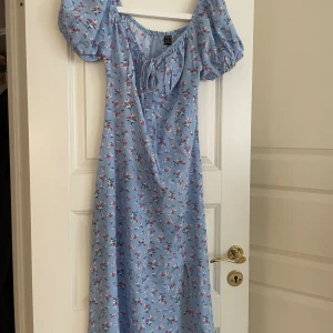 Blommig klänning med slits - Är i jätte bra skick, använd 1 gång.  Är 159cm och den sitter perfekt i längden.  Köpte den för 149kr. Priset kan minskas. 