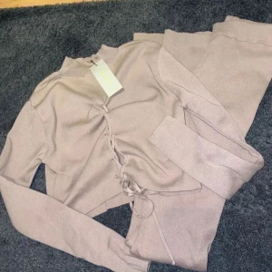 Stickat set - Tröjan har en fin snörning i ryggen. Byxorna är utsvängda.  Nypris var: 540kr.