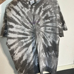 Grå tie-dye t-shirt från Urban Outfitters - Säljer en grå tie-dye t-shirt från Urban Outfitters i storlek M. Den har ett coolt mönster med spiraler och är perfekt för en avslappnad stil. T-shirten är gjord av bomull och har korta ärmar. Perfekt för sommaren eller när du vill ha en chill look. 🌀