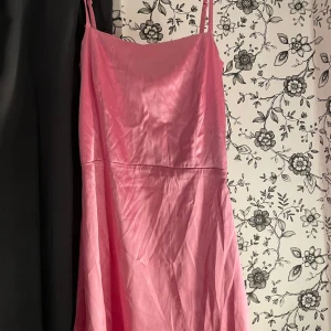Rosa axelbandslös klänning - Säljer en söt rosa klänning med axelband. Klänningen är i ett lätt och luftigt material, perfekt för varma sommardagar eller en festlig kväll. Den har en enkel och elegant design som gör den lätt att matcha med olika accessoarer. Lite skadat nere på klänningen men inte mycket.