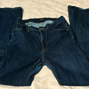 Mörkblå jeans från Lindex - Säljer ett par mörkblå jeans från Lindex i storlek EUR 42 (dam L). Jeansen har en klassisk femficksdesign med dragkedja och knapp framtill. De är tillverkade i ett slitstarkt denimtyg och har en snygg, mörk tvätt som passar till det mesta. 