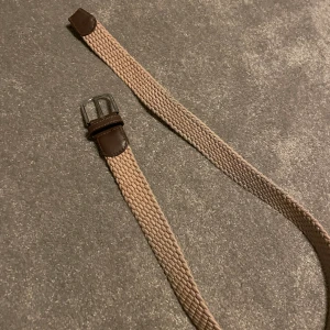 John Henric beige flätat bälte - Säljer detta fina flätade bälte, skick 10/10 bara testad aldrig använt. Köpt för 550kr på NK, skriv pm för fler bilder!