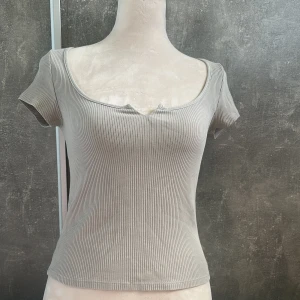 Kortärmad gråbeige tröja - Denna tröja är helt ny men är inte min stil.  Den är i bra skick och har jättefin urringning och material. Färgen på tröjan är gråbeige. Skriv om intresserad💞 