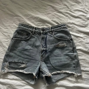 Jeansshorts Cheap Monday - Blå jeansshorts med slitningar från Cheap Monday. Stl S. Bra skick