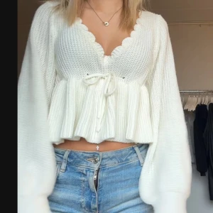 Stickad blus - Söt stickad blus som har volang nertill och knytning. Den är benvit i färgen. 