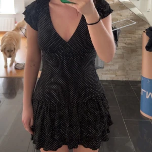 Prickig volangklänning - Världens finaste volangklänning! Svart med vita prickar, jag har dragit upp klänningen lite då den egentligen är ca 5-10 cm längre💕 Storlek S men sitter mer som en M, passar nog även L då den är i stretchmaterial🫶🏼