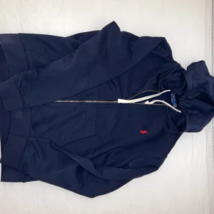 Polo Ralph lauren zip hoodie - Mörkblå polo kofta som sitter riktigt skönt och är perfekt att köra nu till våren.  Helt i nyskick. Priset är ej hugget i sten så vid snabb affär kan det sänkas 