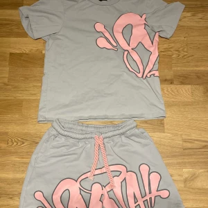 Syna World tracksuit/summer set - Syna world tracksuit/summer set. Ingår 1x tshirt och 1x shorts samt klistermärken och förpackningen. Använd fåtal gånger storlek S.