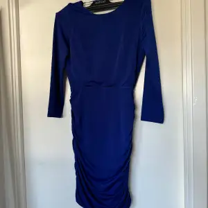En blå mini festklänning med öppen rygg och drapering! Den är aldrig använd!