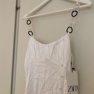 Vit klänning - Klänning från Zara. Oanvänd med lappen på. Fint band med smycke. Storlek 38