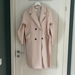 Kappa Witchery  - Ljust rosa/beige dubbelknäppt vårkappa med skärp i storlek S. Helt oanvänd. Säljs pga för liten. Längd ner till knä. 