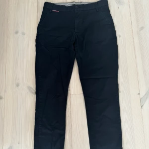 Chinos Tommy Hilfiger stl 164 - Chinos Tommy Hilfiger svarta stl 164. Fint skick. Nypris 899:-/st.  200:-/st  Djur- och rökfritt hem. 