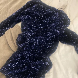 Blå glittrig klänning med paljetter. - Denna klänning är helt oanvänd. Den är jättefin på men den kom aldrig till användning.