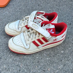 Röda adidas 38-3/4 - Snygga vita och röda adidas sneakers. Väldigt sparsamt använda. Supersnygga nu till vår/sommar. 