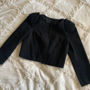 Vintage bolero jacka y2k 90s 90-tal svart ornamenterade axlar - Helt otrolig bolero jacka med fräsiga axlar och tryckknapp  Storlek S (36)  Längd 45cm Bredd 38cm Ärmlängd 52cm Ngt slags lite grövre canvastyg och troligtvis polyester foder.  Tre stycken tryckknappar. Spår efter att det funnits fler men dem är bort