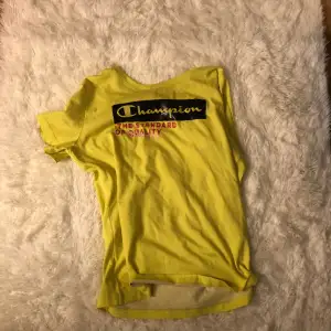 En gul tröja med en text som har svart runt sig och skrivit i gul och under en rosa text