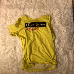 En gul T-shirt  - En gul tröja med en text som har svart runt sig och skrivit i gul och under en rosa text