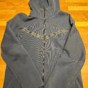 Nike Tech tröja i storlek S - Tja, säljer nu mina gamla Nike techs i mörk blå och beige för ett väldigt bra pris! Den är ca 2,5 år gamla och jag har tyvärr inte kvar kvitto för den anledningen. Båda tröjorna har små skador till dragkedjebandet men inget man inte kan fixa! 300kr!