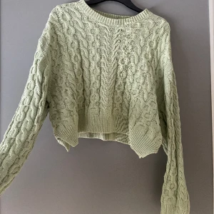 Grön kabelstickad tröja - Grön kabelstickad tröja från pull and bear, i stl M o är lite mer åt det croppade hållet än oversize. Superfin färg o bra skick. Frakt är ej inräknat i priset 😊