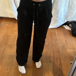 Svarta mjukisbyxor - Ett par svarta mjukisbyxor med dragsko i midjan. Byxorna har en lös passform och är bekväma för vardagsbruk.