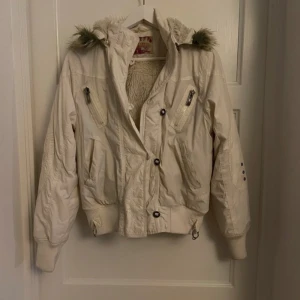 Cool jacka - Snygg vit vinterjacka med en pälsluva och massvis med fickor. Fodrad på insidan och riktigt skön. Dragkedjan funkar ej men finns knappar så den går att stänga. Står storlek L men skulle snarare säga S/M
