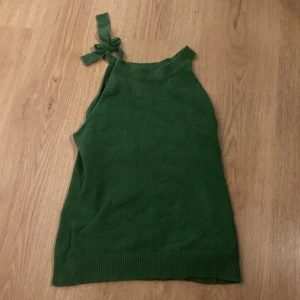 grön linne topp - en jättegullig grön topp med rosett på axeln, passar perfekt till jul. vet inte vart det är ifrån eftersom lappen tyvärr är bortklippt. säljer eftersom den tyvärr inte kommer till användning.