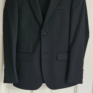 Kostym - Svart kostym från Dressman. Använd 1 gång. Som ny! Storlek 44 på kavaj, byxa 29/30. NYPRIS 2000 KR. 