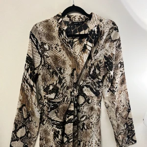 Klänning - Klänning med ormskinn mönster i storlek xs! Aldrig använd, knyter i midjan.