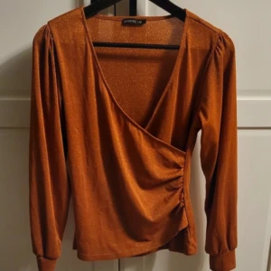 Omlott-topp från Stockh lm - Glittrig och fin! Sitter fint och framhäver figur. Nyskick!  Färgen är typ koppar/brun/orange