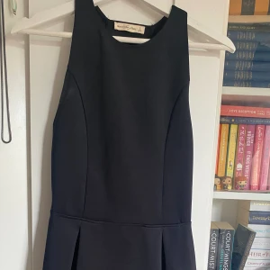 Svart festklänning  - Stilren svart festklänning, endast använd en gång! Bild nr 2 är baksidan (den är delvis öppen i ryggen. Tjockt material, känns sportig.