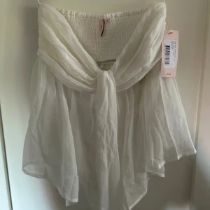 Tubtopp från Nelly - En skit snygg vit flowy topp från Nelly som är slut såld! Aldrig använd med prislapp kvar! Den har då inga defekter då den aldrig använts! 