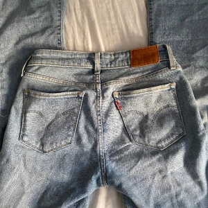 Levis 715 bootcut jeans - Low waist bootcut jeans från levis, egetgjort hål på ena benet, bra skick. Köparen står för frakt. Storlek 24. Passar mig som har storlek 32-34. Avklippta längst ner men passar ändå mig som är 168