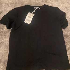 T-shirt - Säljer min svarta t-shirt med en ficka som aldrig andvänds. 