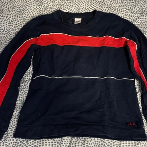 Mörkblå sweatshirt - Mörkblå sweatshirt med röd rand från Lingon&Blåbär. Storlek 150 men passar även XS-S. Lite ljusare i verkligheten än den ser ut på bilden.